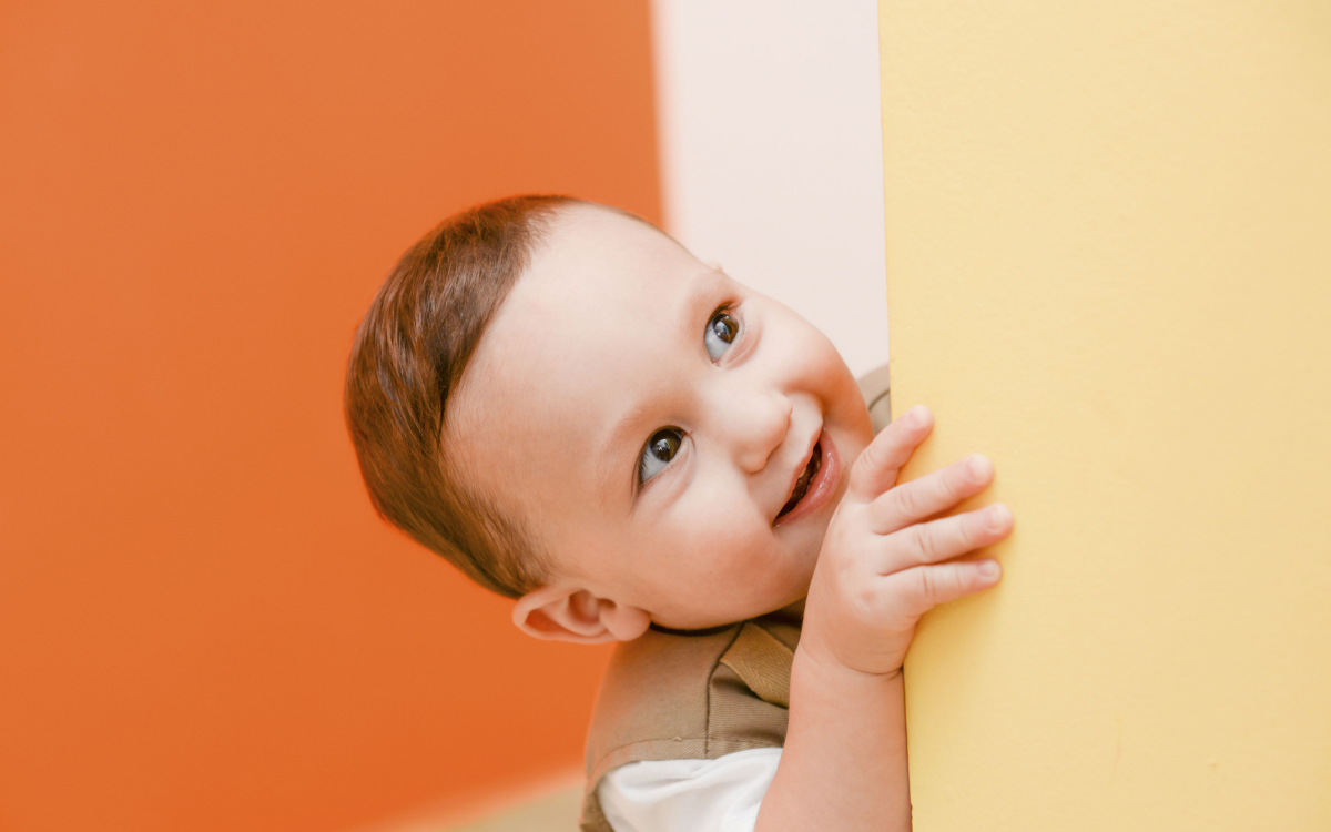 Cute toddler peeking from behind a wall
